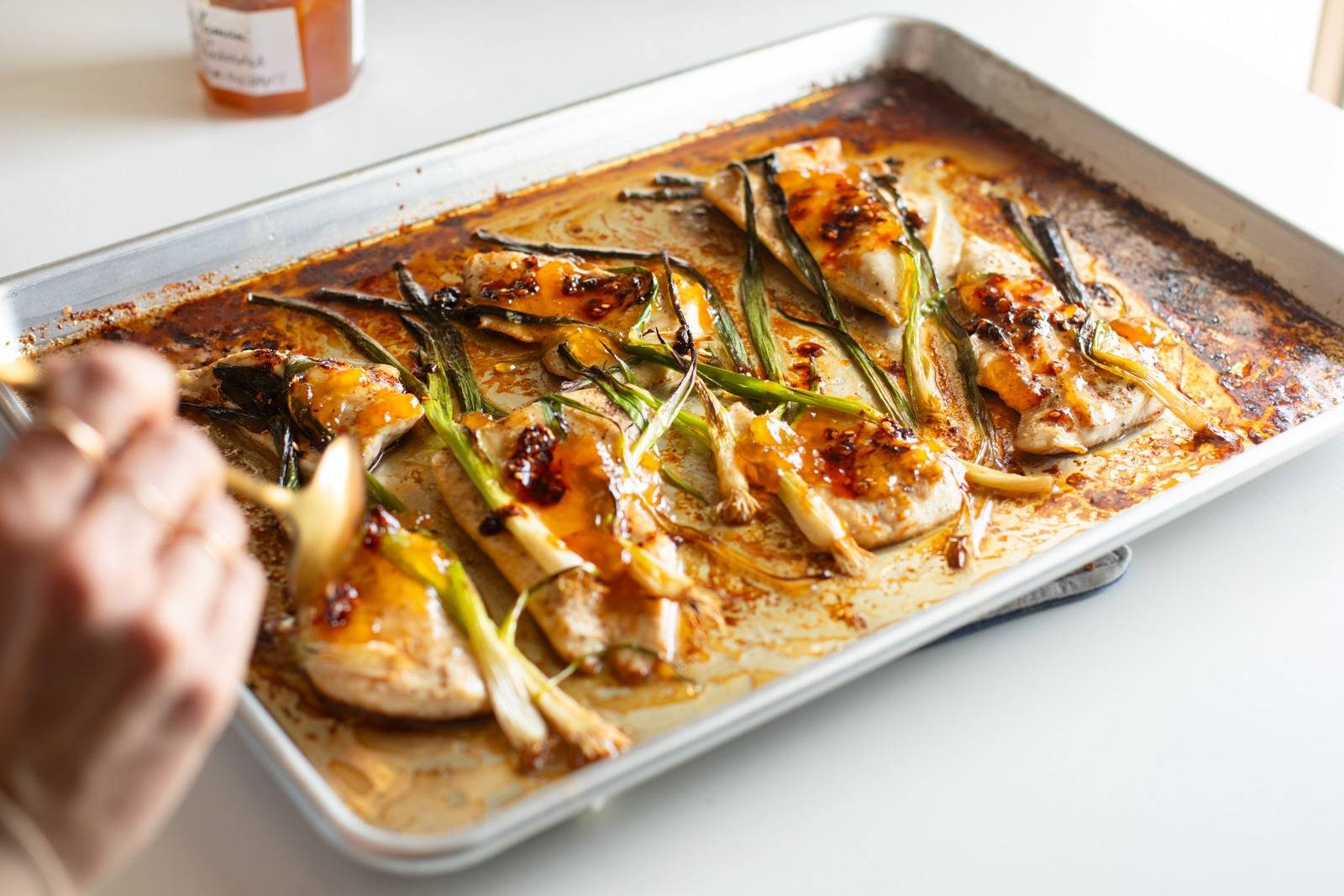 Baked chicken and scallions on a sheet pan.