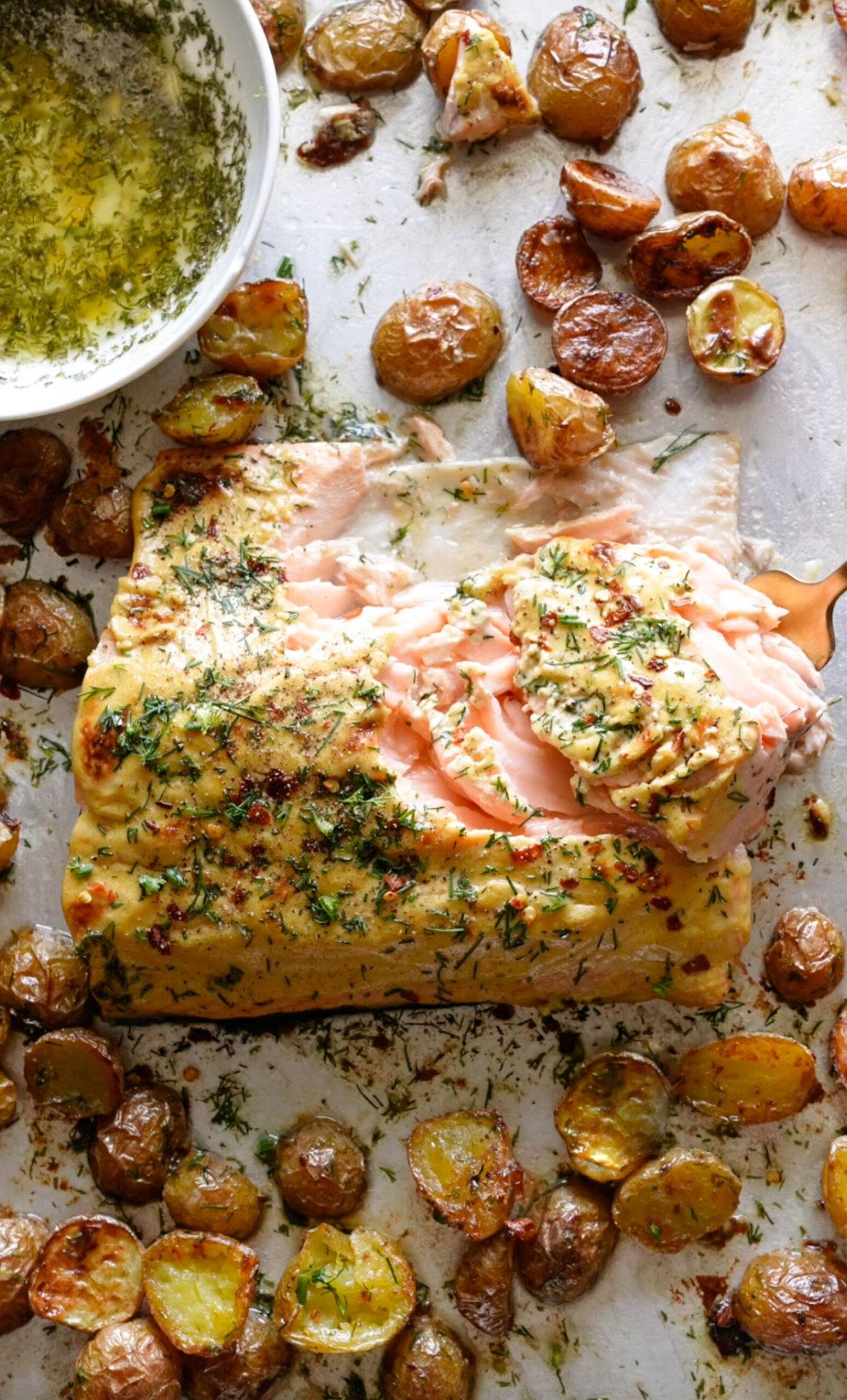 Salmon and potatoes on a sheet pan covered in dill.