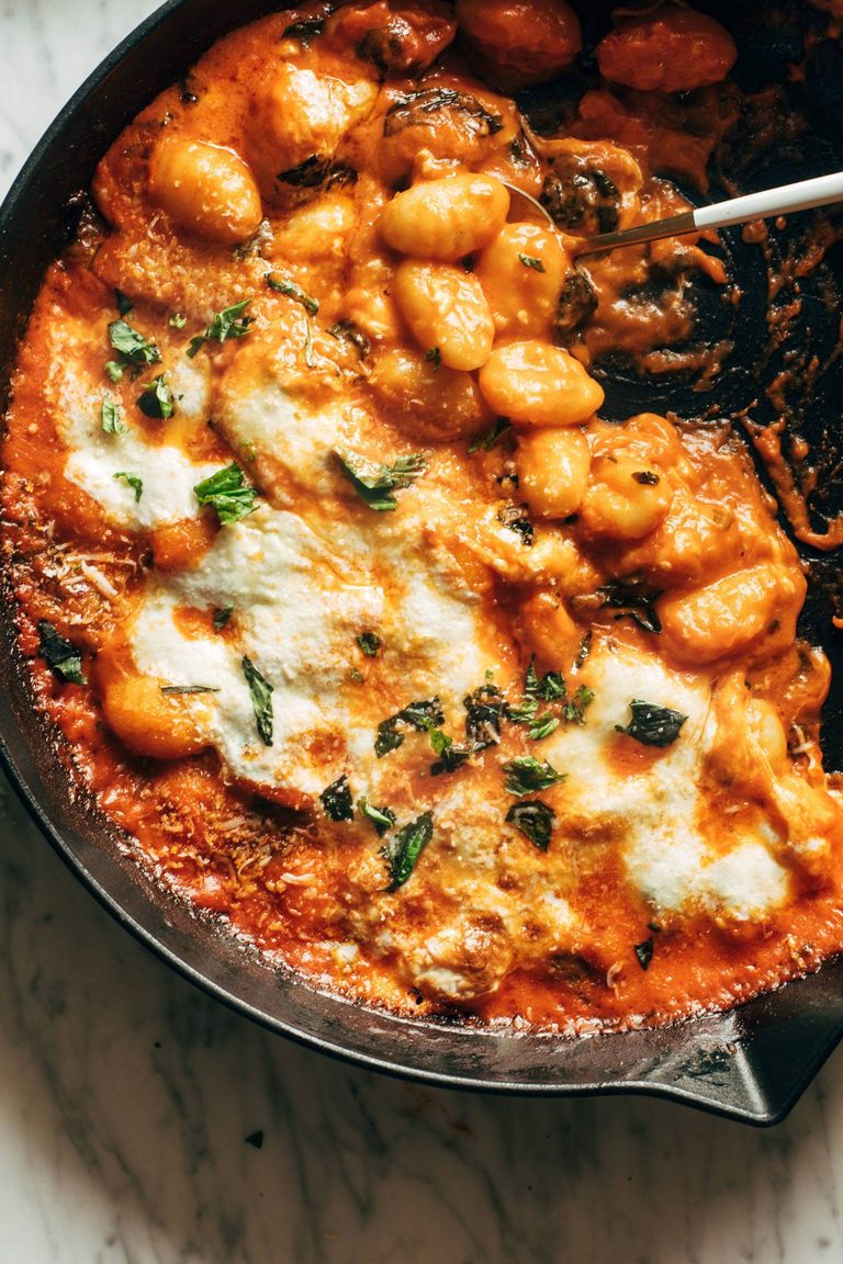 Three cheese baked gnocchi with spinach in a skillet.