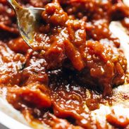 A spoon reaches into a tomato sauce.