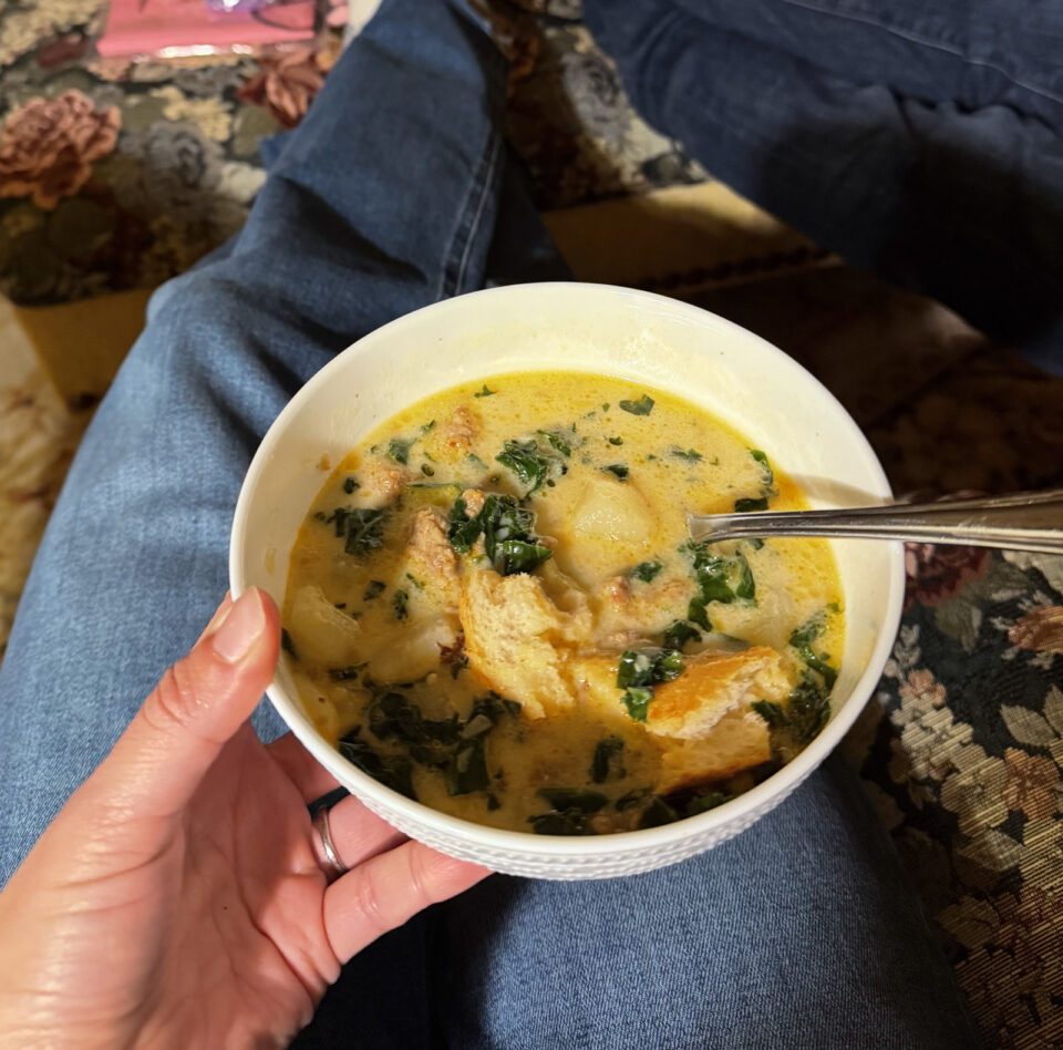 Zuppa toscana in a bowl with bread on top.
