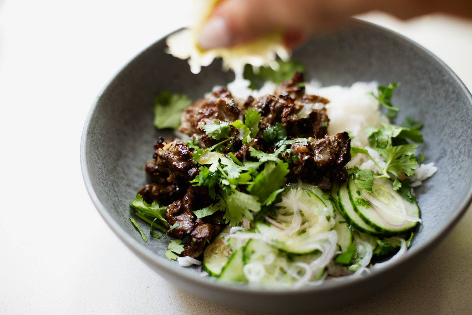 Beef and cucumbers in a bowl with rice.